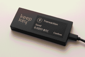 KeepKey cryptocurrency hardware wallet on a light background with display showing transaction details